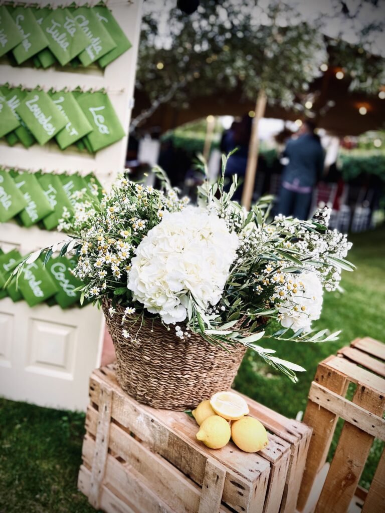 Centro floral blanco junto a un seating plan con tarjetas verdes en una boda