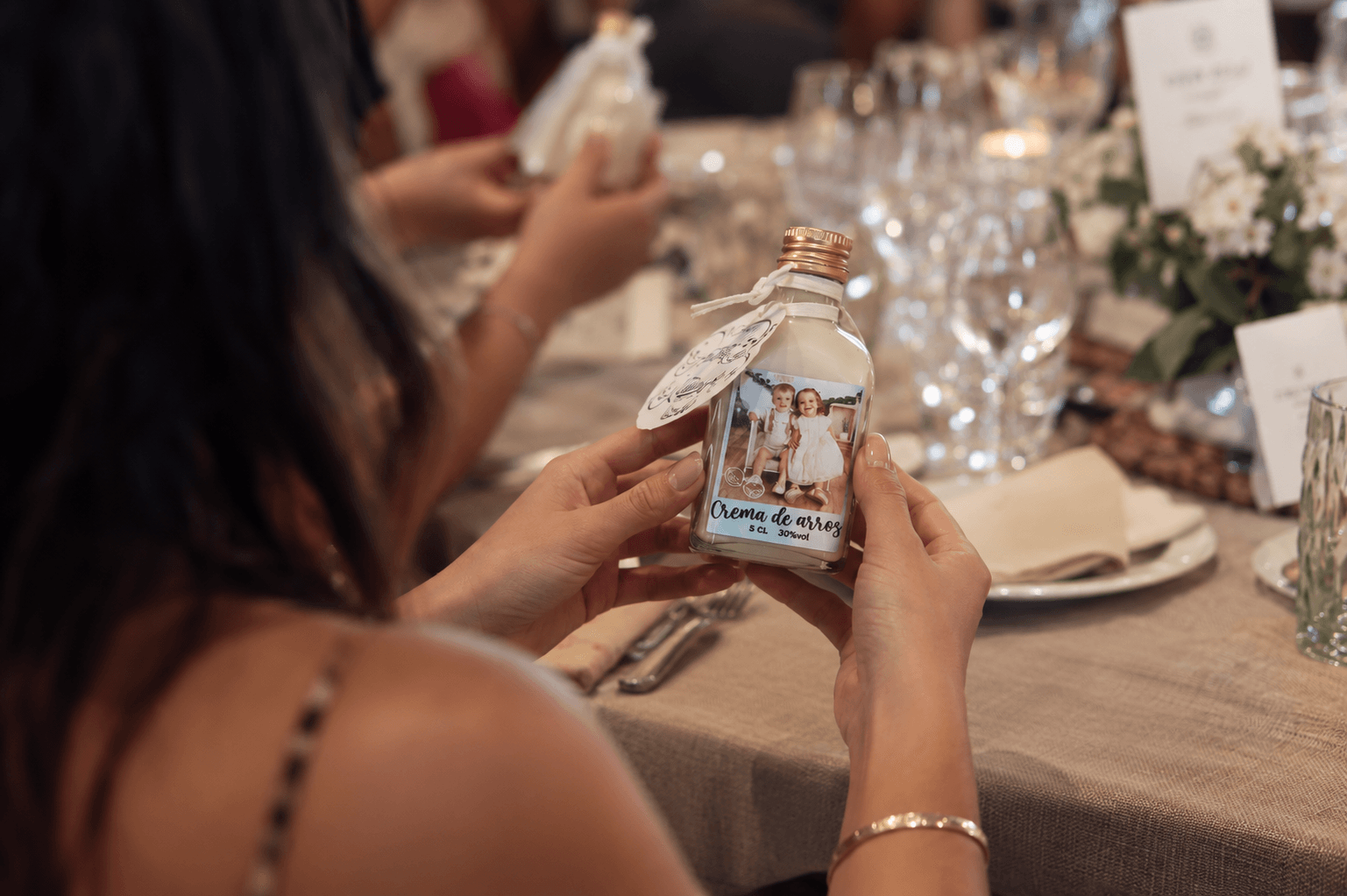 Invitada sosteniendo una botella de licor personalizada como detalle de boda