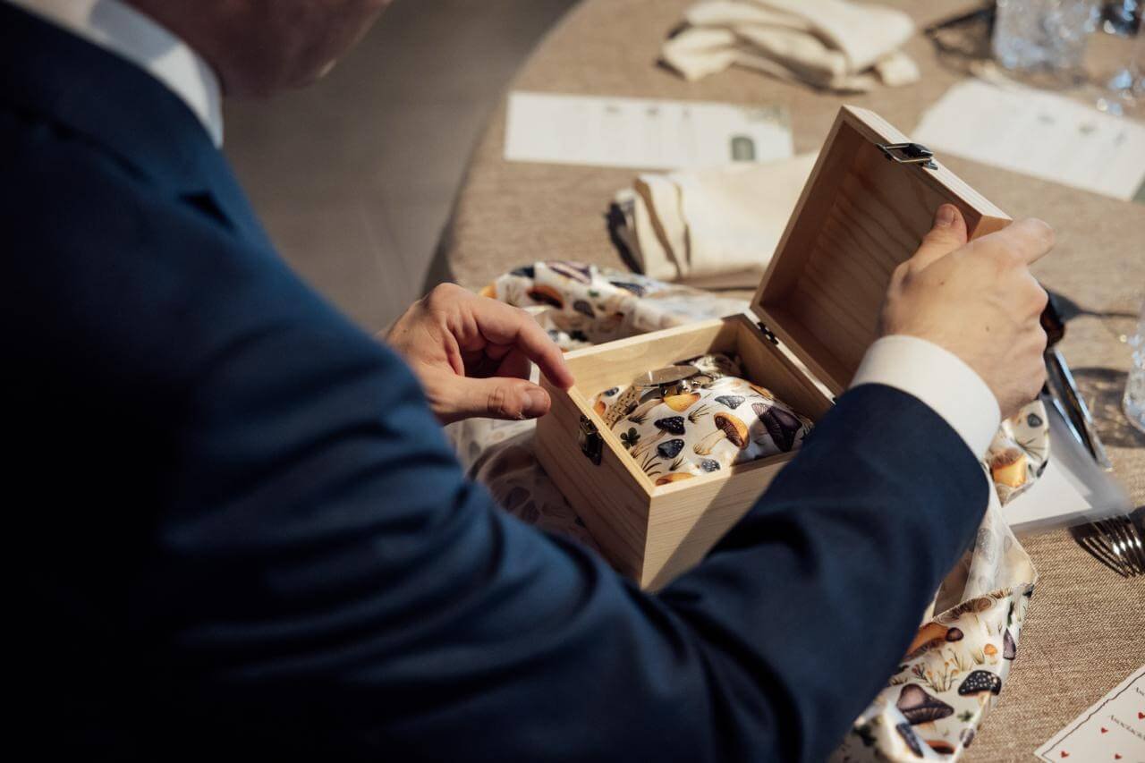 Invitado abriendo una caja de madera con regalo personalizado en la boda