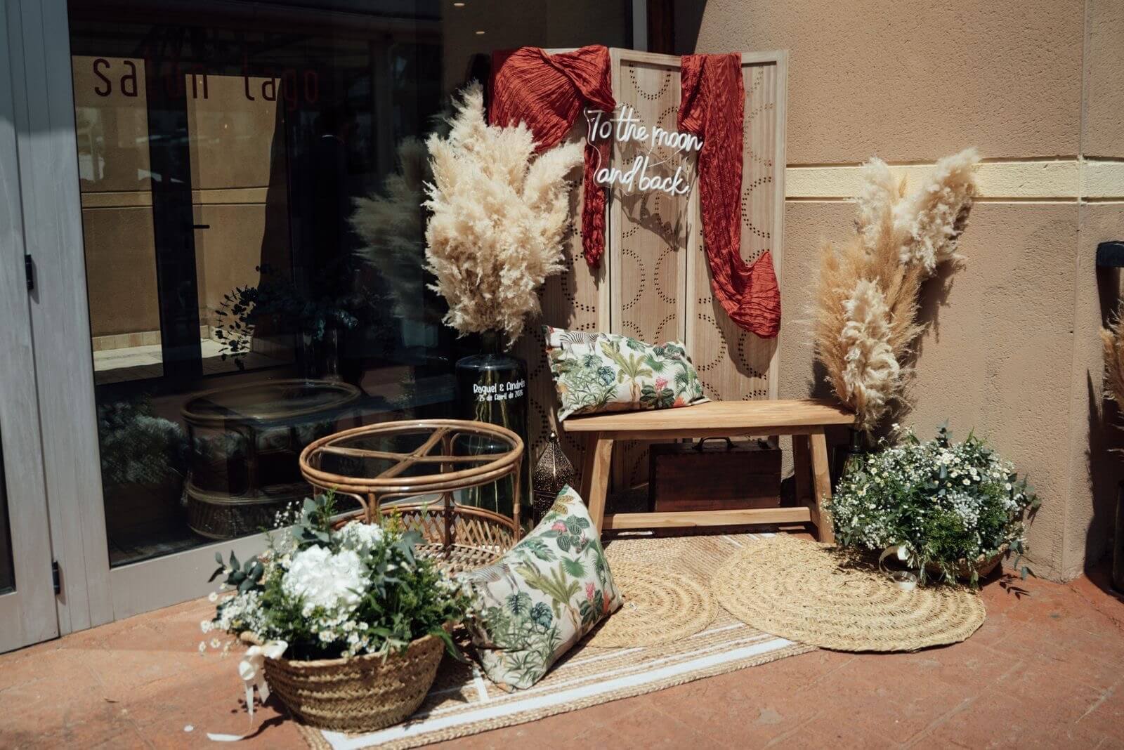 Rincón de boda decorado con flores, pampas, banco de madera y fibras naturales